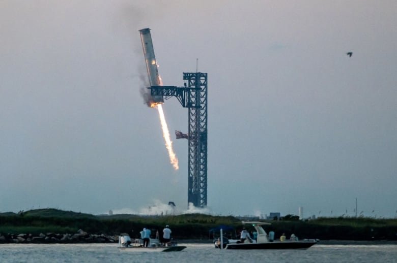 2177494351-1 A booster rocket is grabbed by metal arms at the launch pad.