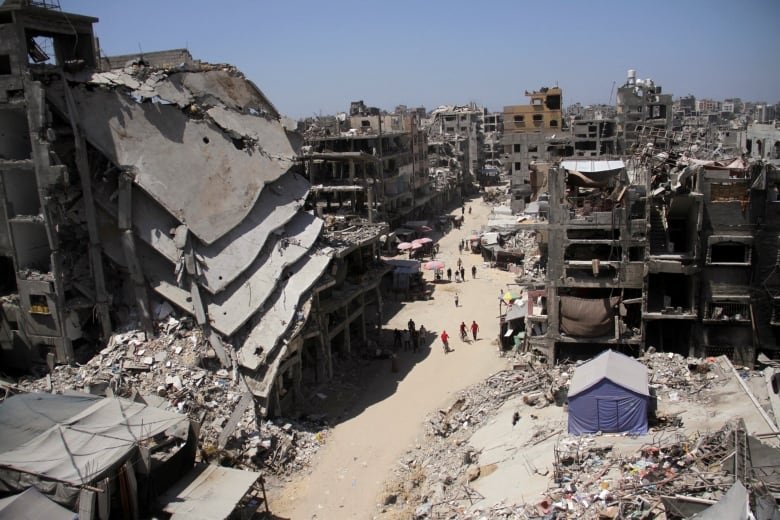 People walk near the ruins of houses destroyed.