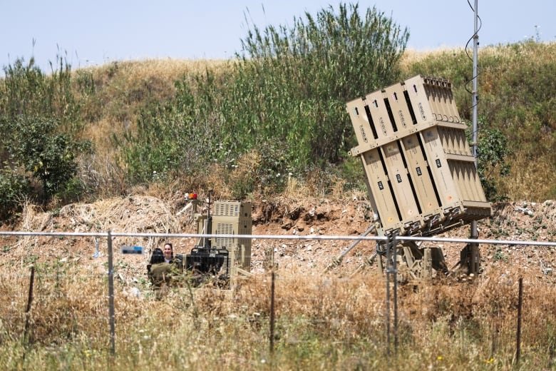 A missile launcher, partially concealed amid an arid landscape, aims skyward.