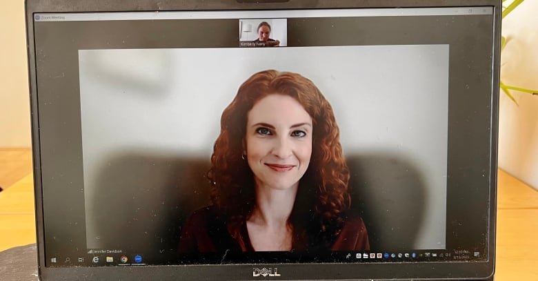 jennifer-davidson A smiling woman with red curly hair is seen a laptop screen.