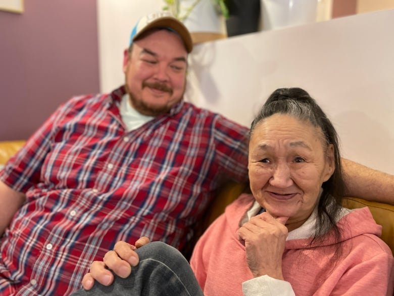 kitty-noah-and-noah-noah A man smiles at an older woman seated next to him on a couch.