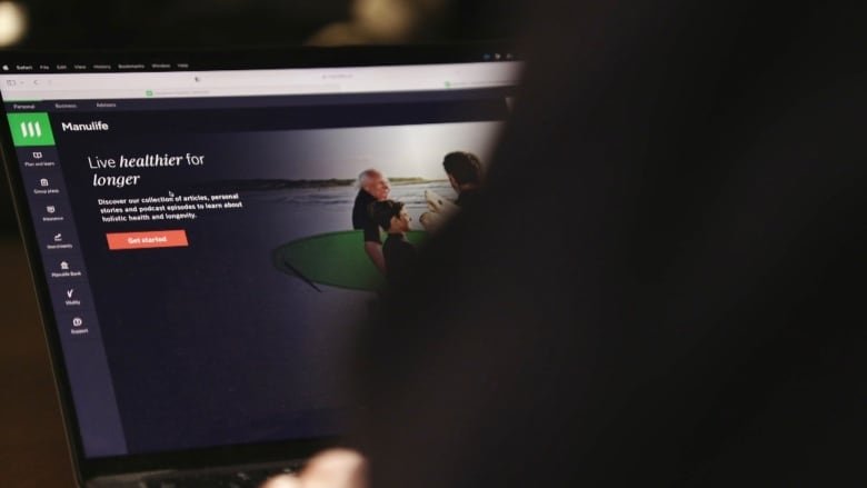 manulife-insider-screen An over the shoulder view of a person in shadow. They are looking at a page on Manulife's website on a laptop.