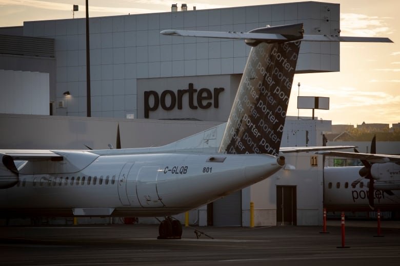 porter-grounded A small Porter aircraft is parked in front of Billy Bishop Airport at dusk.