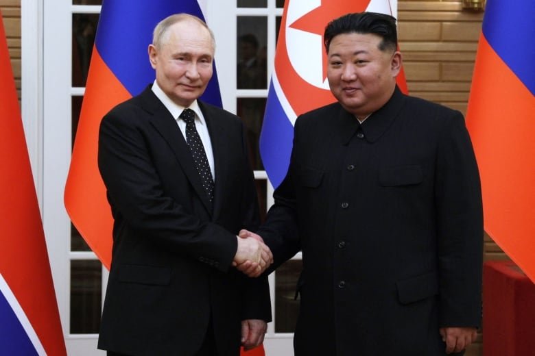 putin-and-kim-jong-un Russian President Vladimir Putin shakes hands with North Korea's leader Kim Jong in front of their country's flags during Putin's visit.
