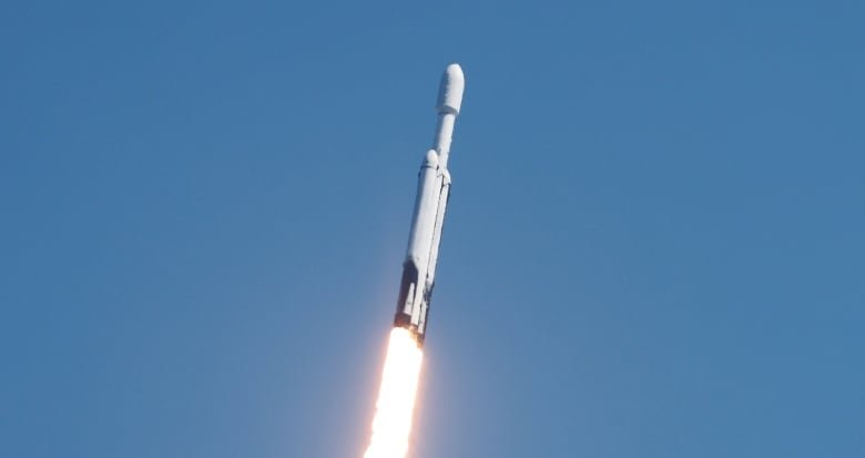 space-exploration-europa-2 A white rocket is pictured mid-flight through blue skies, heading upwards with a jet of white flame tinged with red spitting out of the back of it.