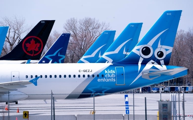 transat-air-canada-20201106 The tails of five airliners are seen on an airport's tarmac.