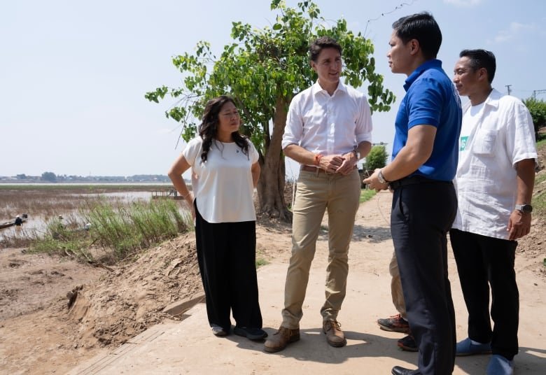 Prime Minister Justin Trudeau speaks with Chief Executive Officer of the Mekong River Commission Secretariat Anoulak Kittikhoun and fisherman Laittikay as Export Promotion, International Trade and Economic Development Minister Mary Ng looks on along the bank of the Mekong river in Vientiane, Laos, Friday, Oct. 11, 2024.