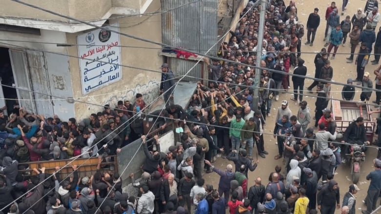 Hundreds of people lining up outside a bakery.