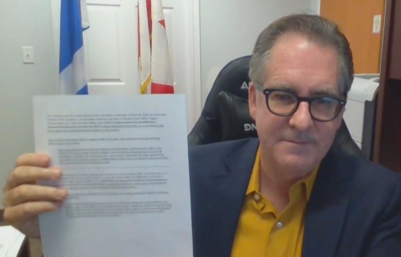 brian-masse Man sitting in office holding paper up to the camera.