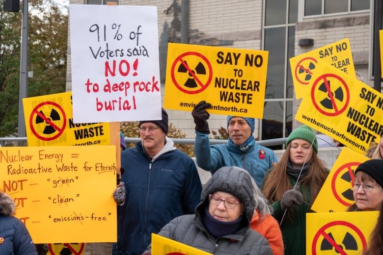 A crowd of people holding bright yellow protest signs.