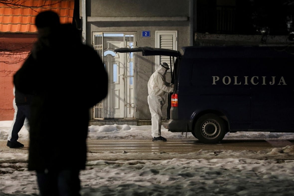 montenegro-shooting-1 A forensics investigator wearing full personal protective equipment reaches into the back of a police van.