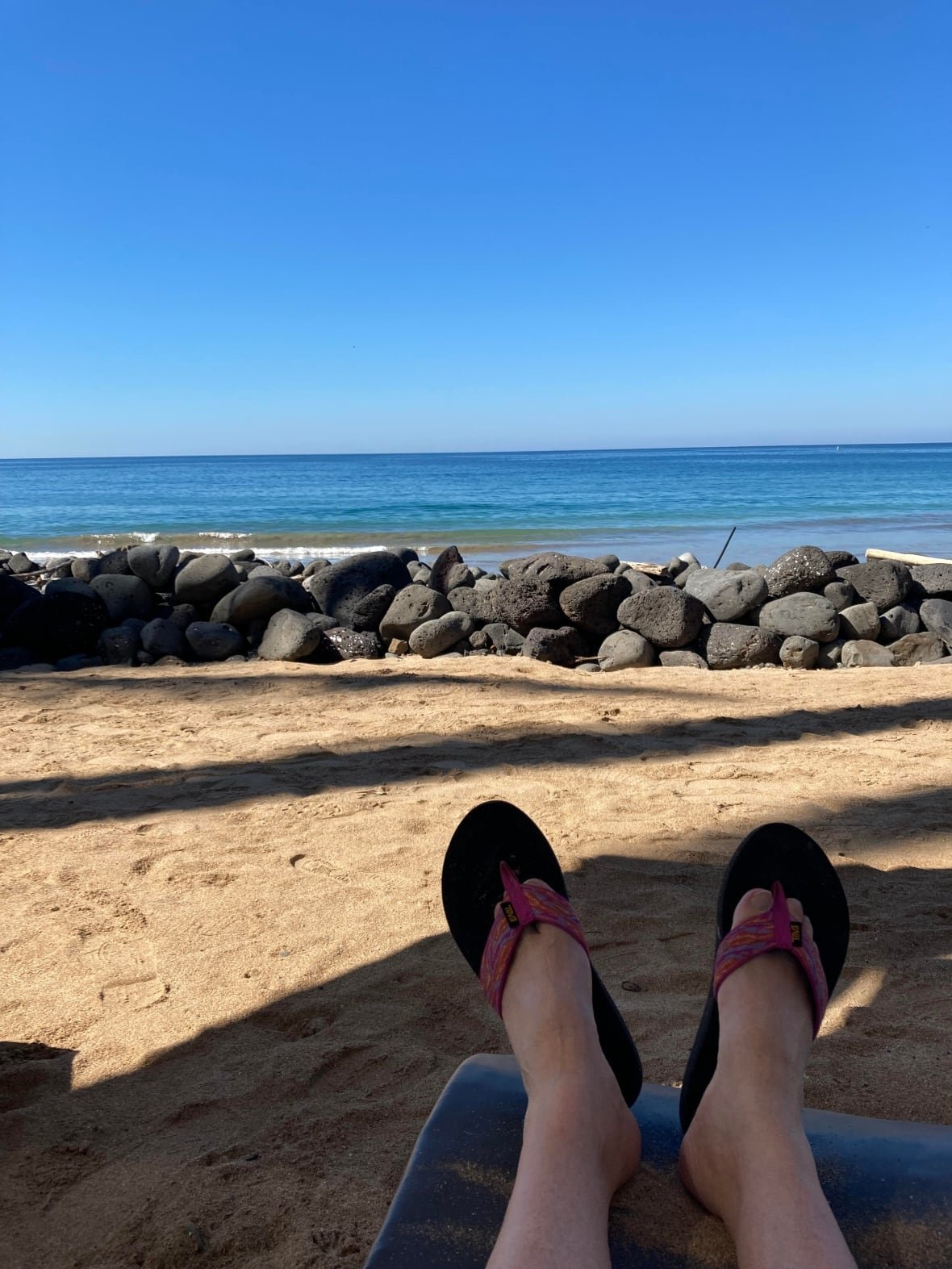 A picture of someone's feet with the ocean in the background.