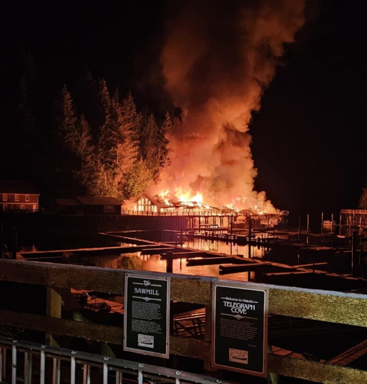 telegraph-cove-boardwalk-fire A wooden restaurant on the shoreline is engulfed in flames.