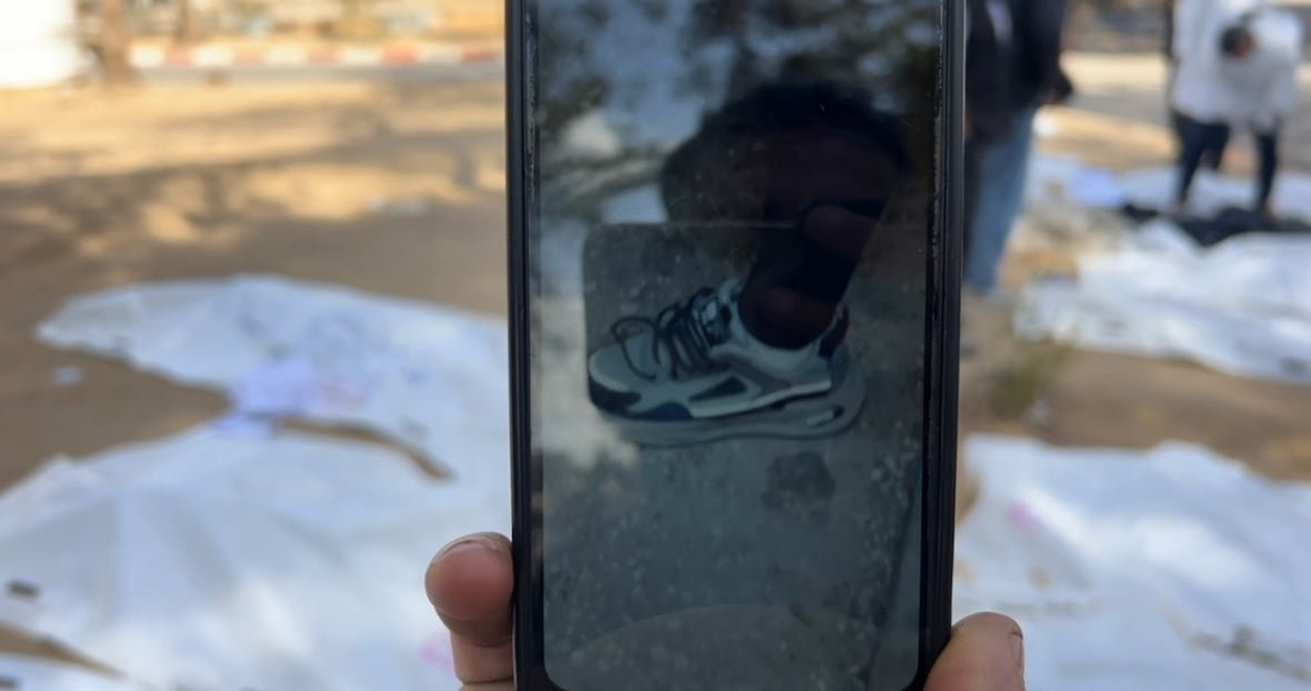 a-man-holds-up-a-photo-of-a-shoe A man holds up a photo of a shoe.