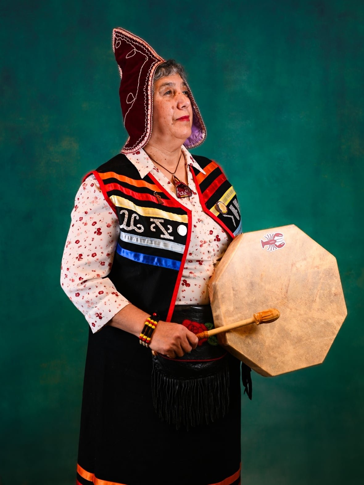 beverly-jeddore A woman in Kojua regalia with a drum poses for a portrait.