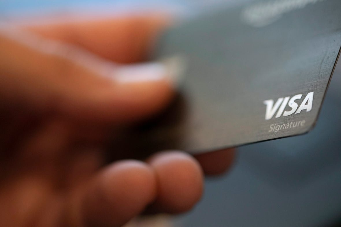 equifax-debt-survey-20221101 Hand holding a Visa card.