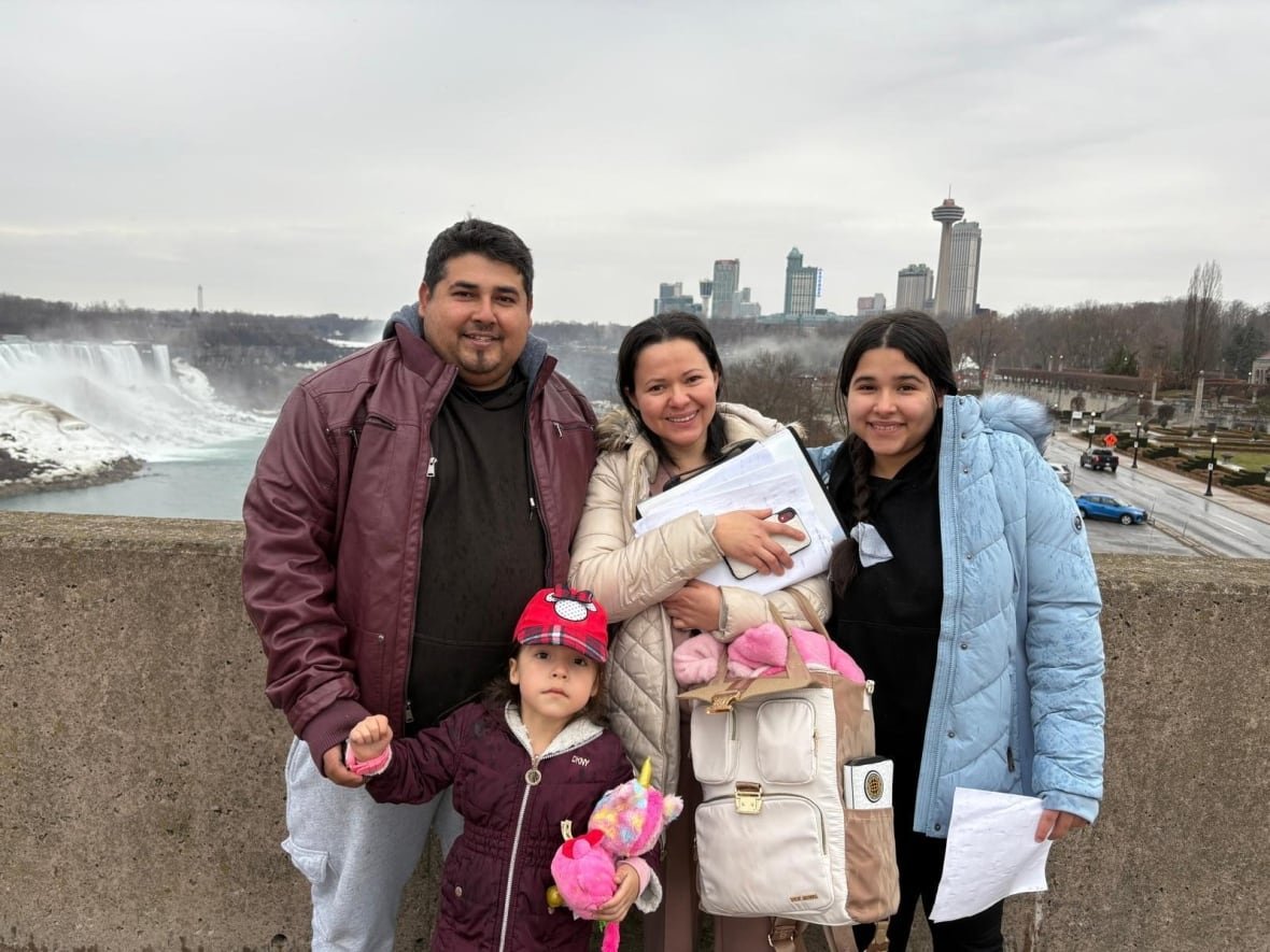 guardado-serrano-family A family of four. The father, on the left, with a young girl between him and the mother, in the centre, and a teenage girl on the right. They are on a bridge in front of Niagara Falls.