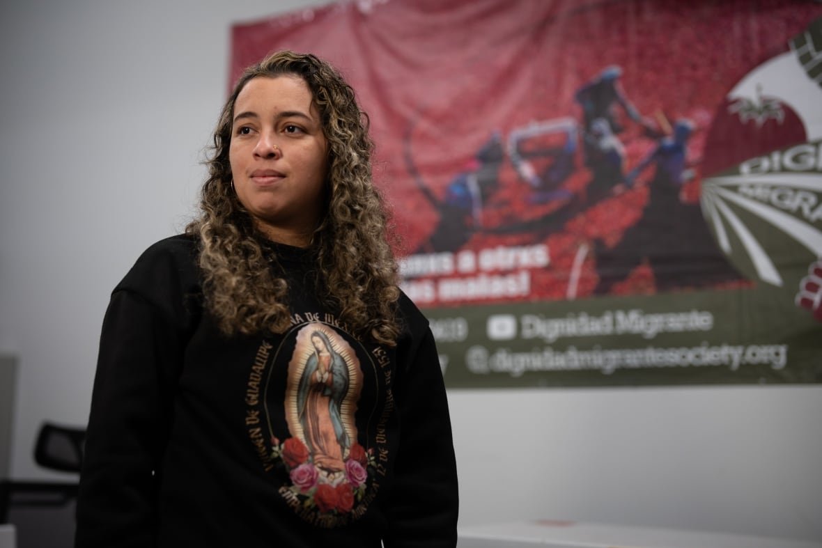 migrant-rights-1 Portrait of a woman with dark, curly hair wearing a black sweater.