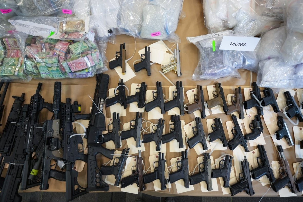 rcmp-bust-20241031 Firearms, illicit drugs and cash that were seized last week are displayed before a news conference at RCMP headquarters, in Surrey, B.C., on Thursday, October 31, 2024.