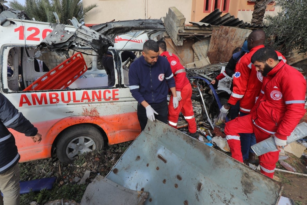 1916335296 Emergency personnel in uniforms are shown near a large piece of metal debris and a damaged ambulance.