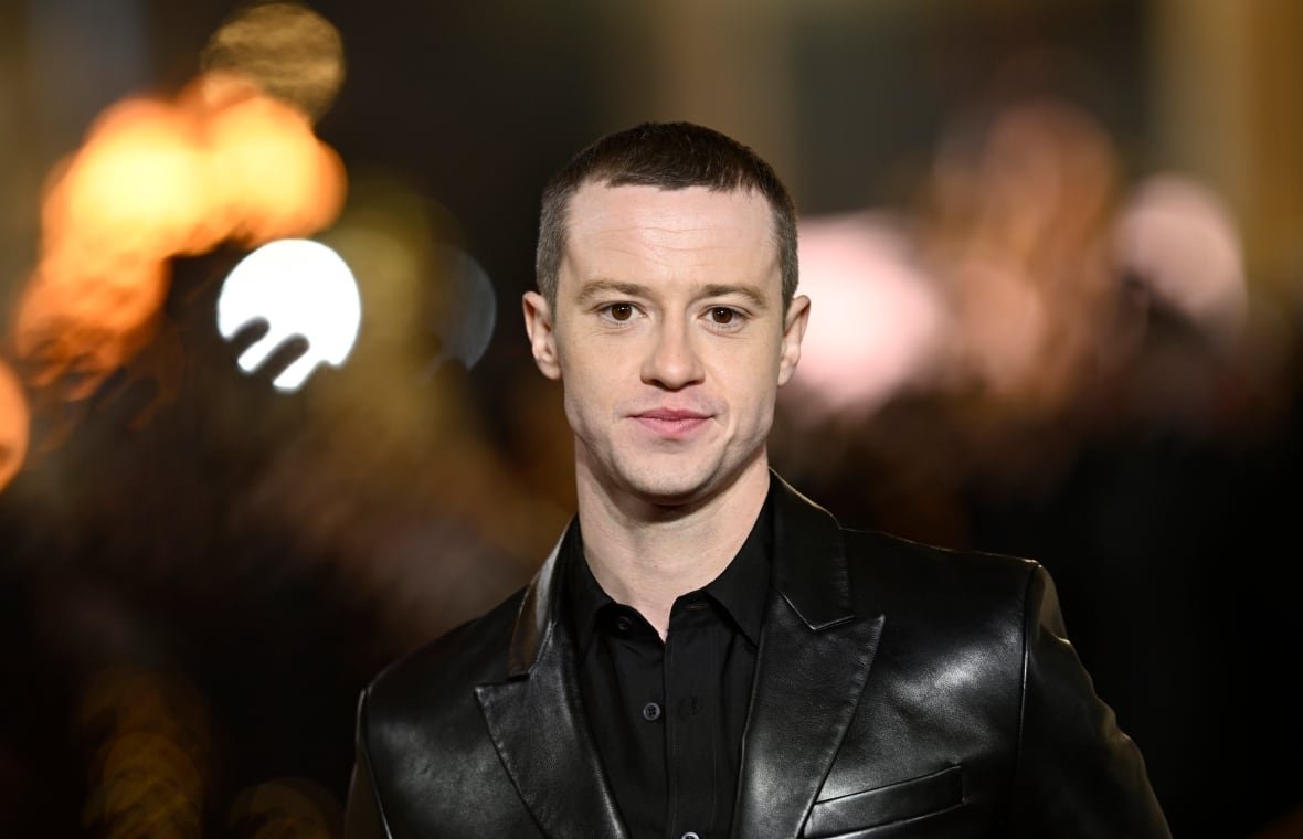 2184623731 A young man with close cropped hair wearing a jacket is shown.