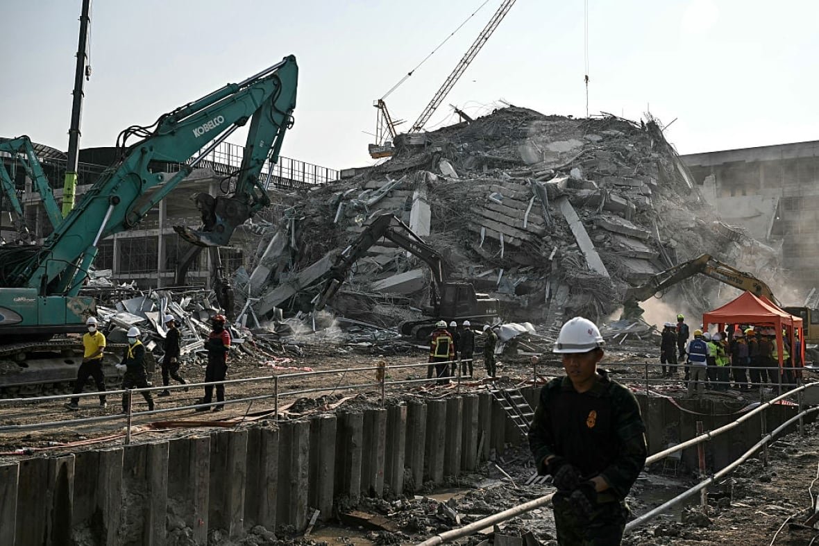 2206826020 Heavy excavating equipment is parked near earthquake rubble.