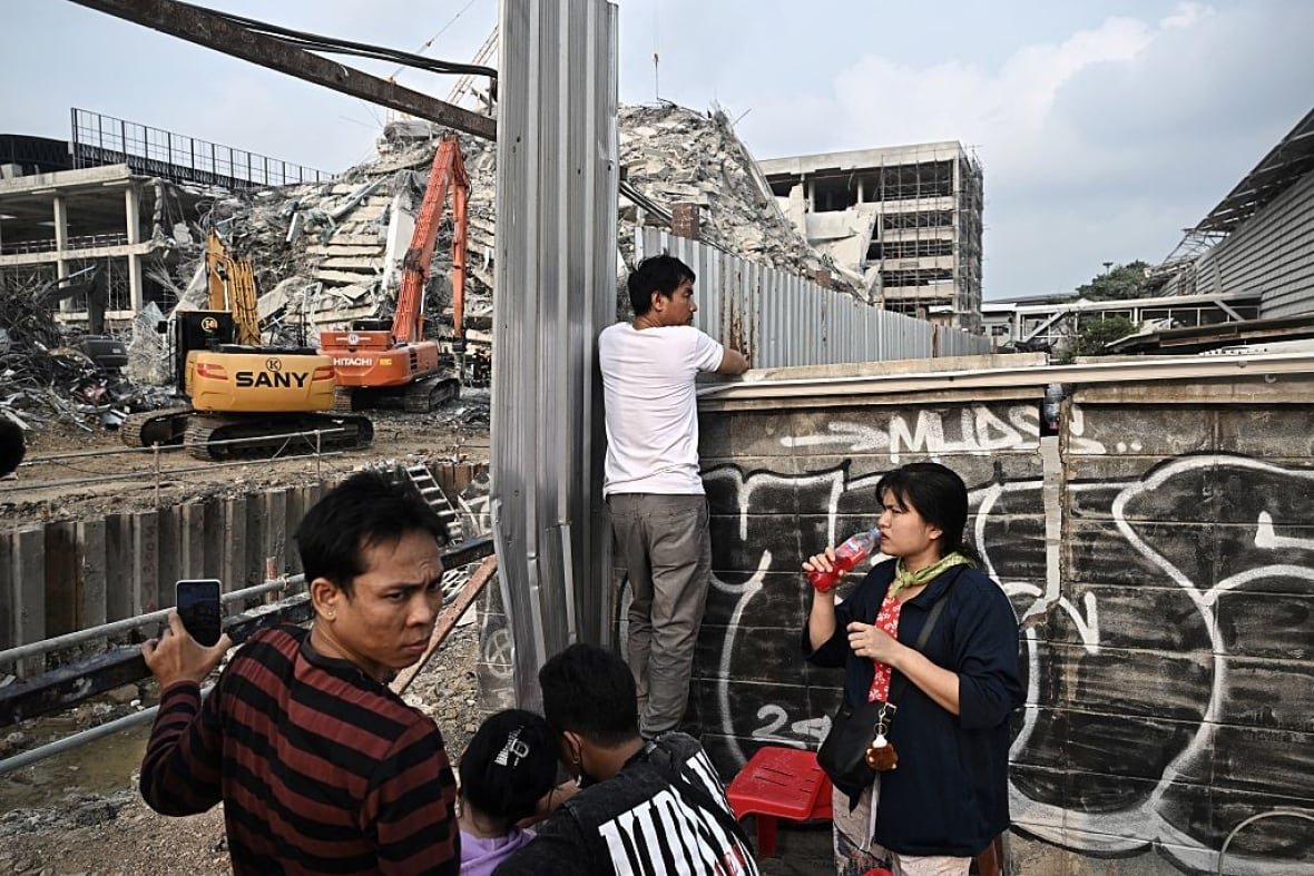 2207011607 Five people wait at the site of a tower collapse following an earthquake
