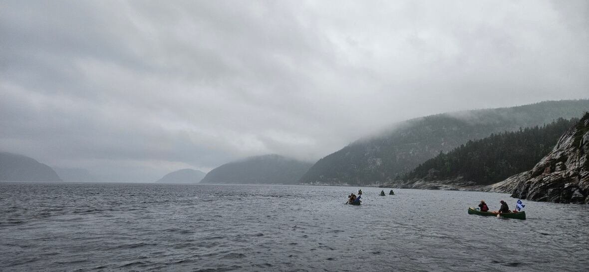 a-la-mer-du-nord-2025-2 A brigade of voyageurs paddling al;ong a misty lake