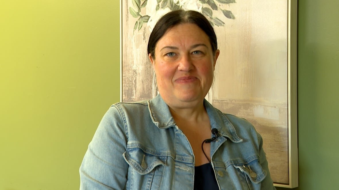 ang-brockway A woman grinning at the camera, standing in a conference room.