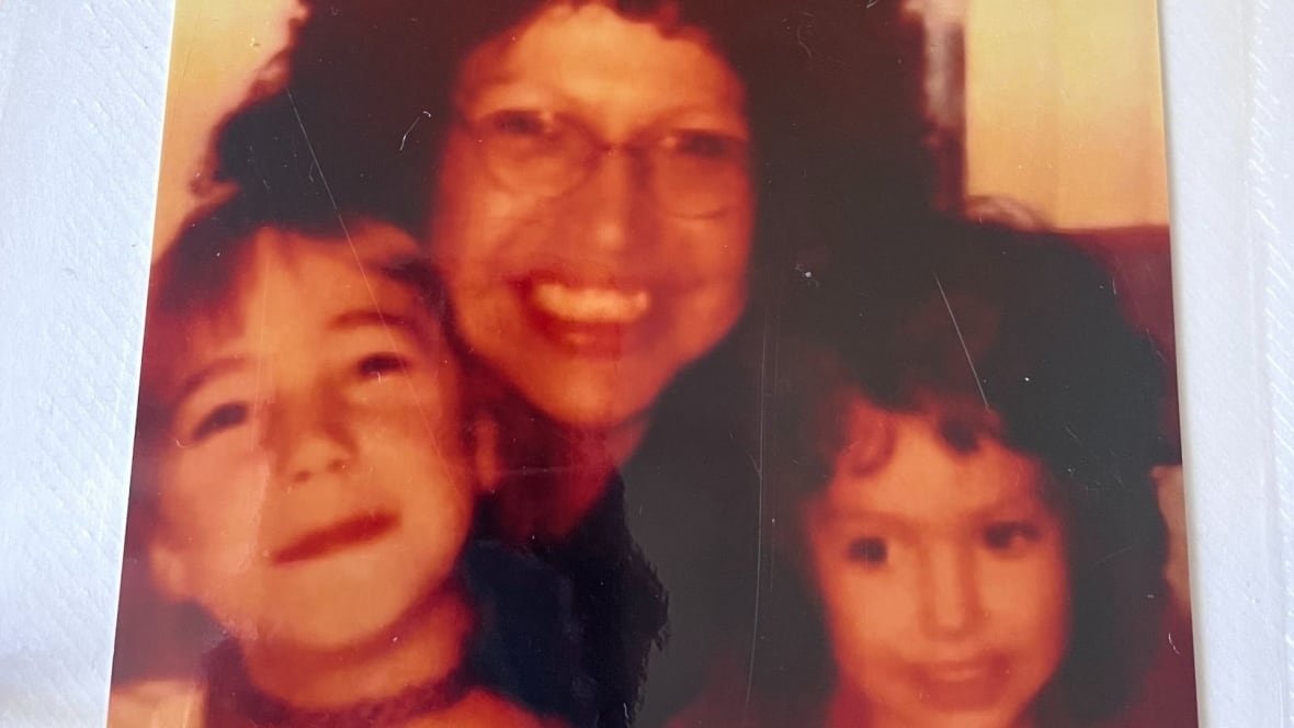 belinda-cameron-and-her-children A woman smiles and the camera holding two children, who also smile.