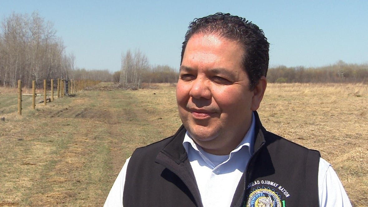 brokenhead-ojibway-nation-chief-gordon-bluesky the chief (a man) stands on the grounds of the farm. fence posts meant to keep the animals in can be seen behind him