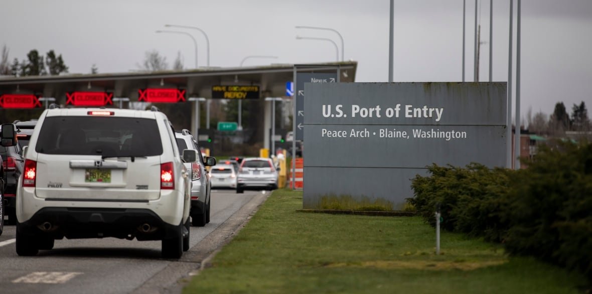 canada-us-border-crossing-bc Cars lined up by a sign that says U.S. Port of Entry.