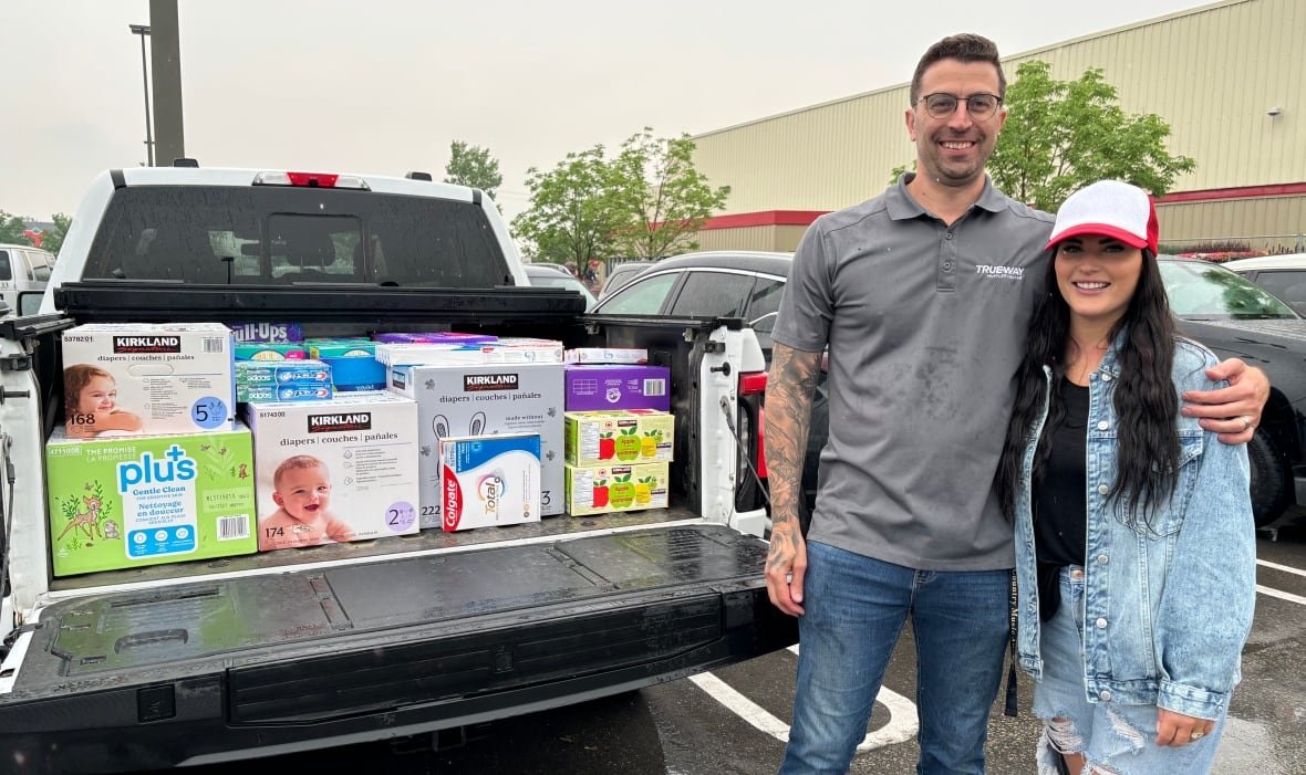 donations-drive-wildfire-evacuees A woman and a man load up the back of a truck with boxes.