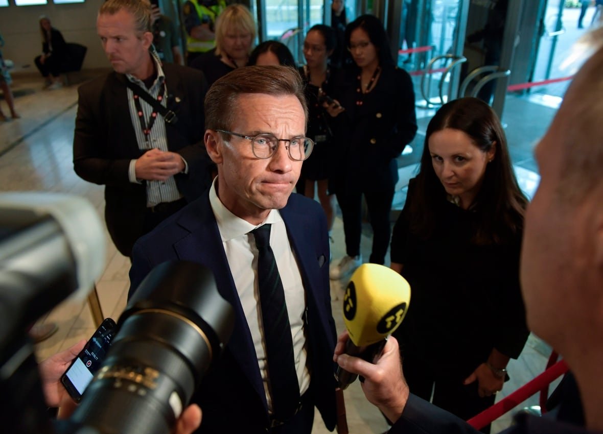 election-sweden A man wearing a suit and glasses is tight lipped as microphones are held in front of his face