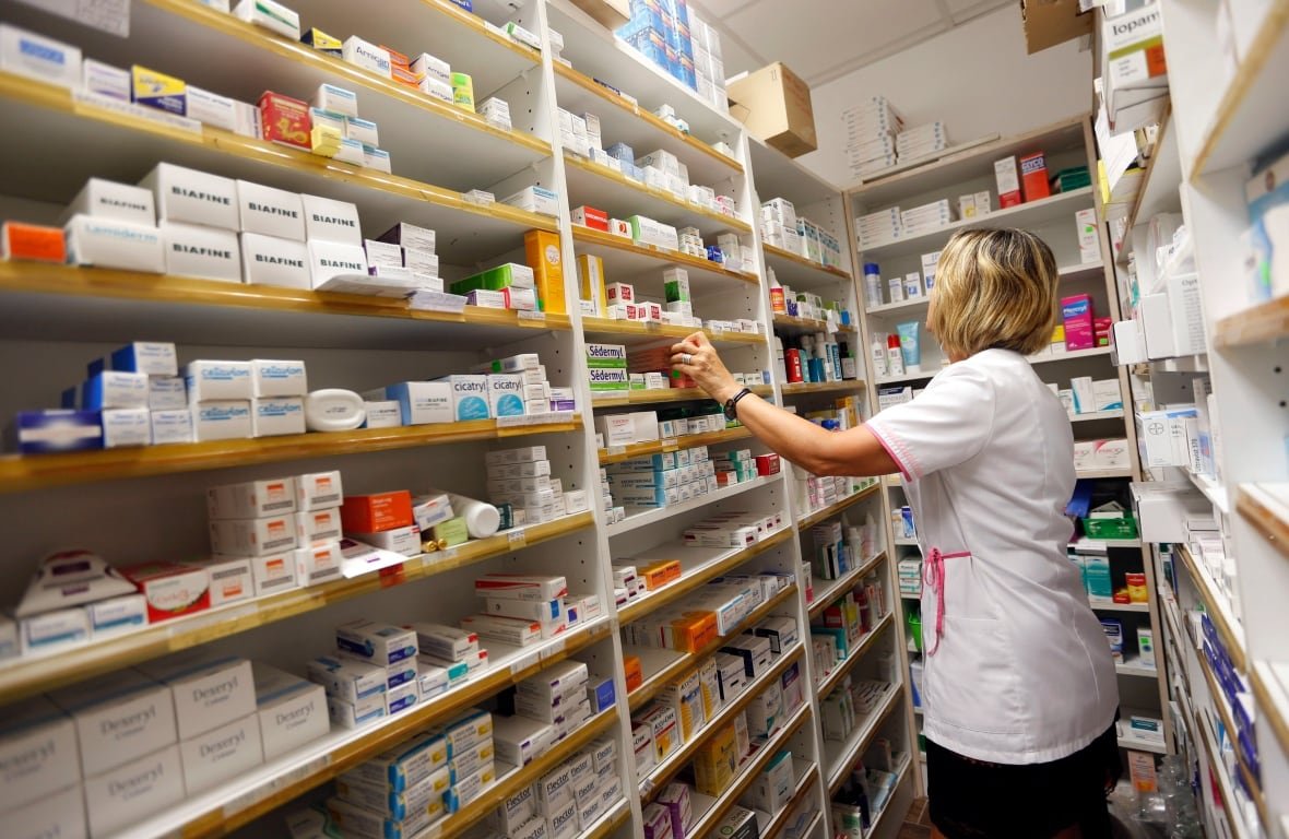 health-pharmacy A pharmacist reaches to shelves with prescription medication.