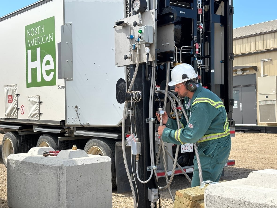 helium-trucks Worker in hard hat connects hoses to a large truck