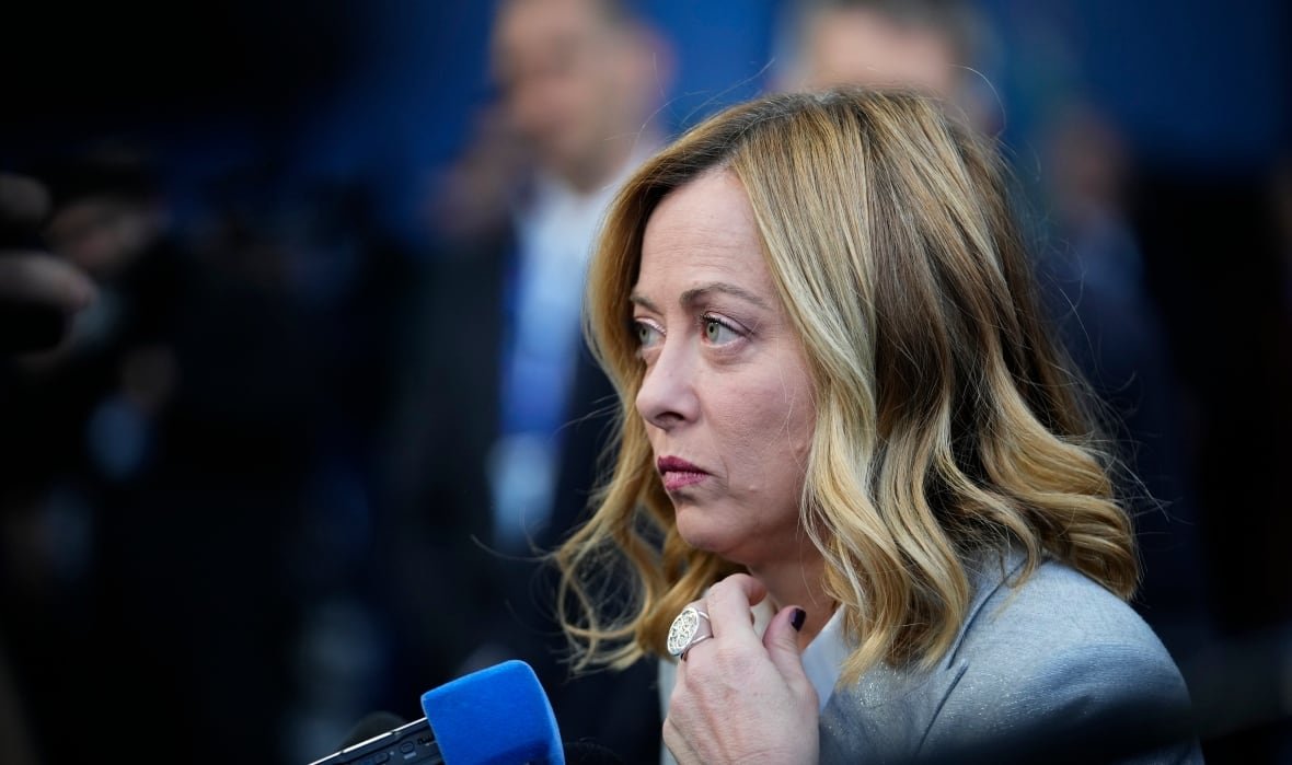 hungary-europe-summit A blonde woman is seen from the shoulders up in profile view, looking to the left of the image. A blue microphone is in front of her.
