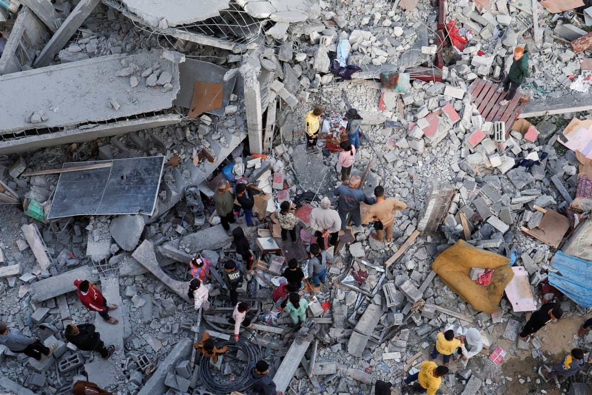 israel-palestinians-gaza-2 People stand atop the rubble.