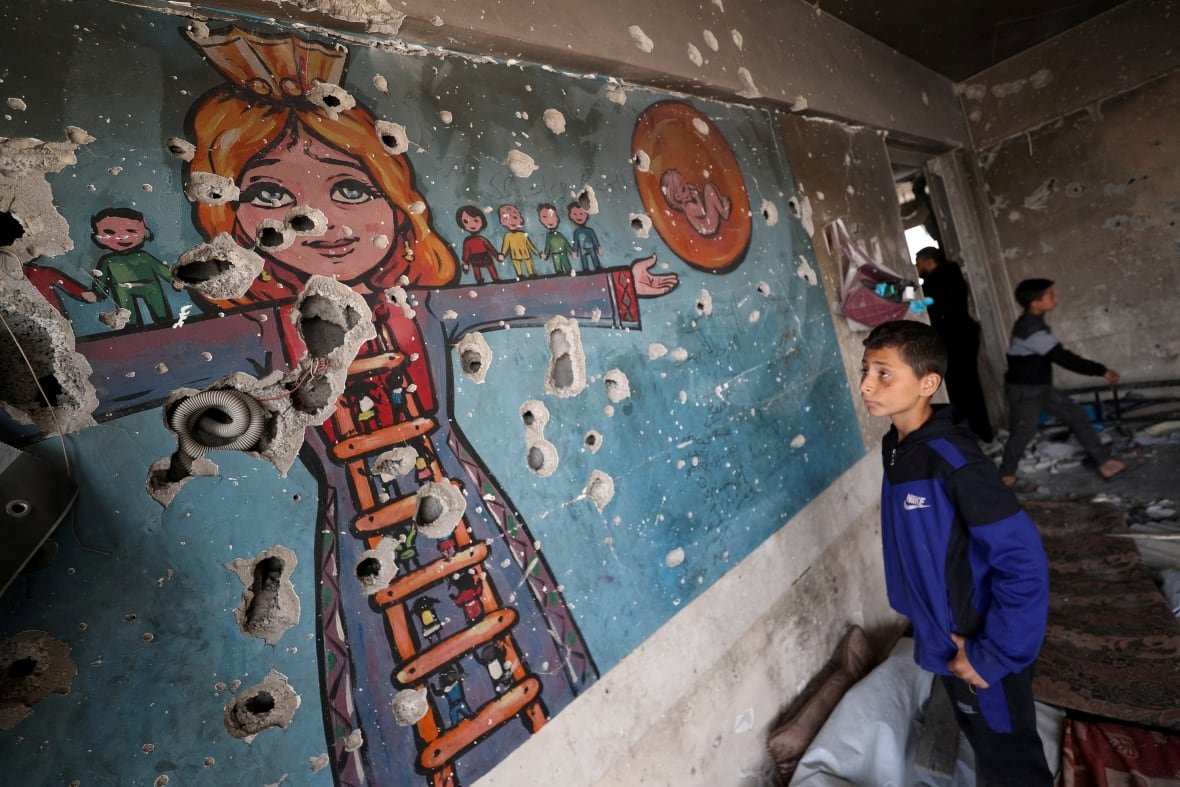 israel-palestinians-gaza-3 A boy looks at a damaged wall.