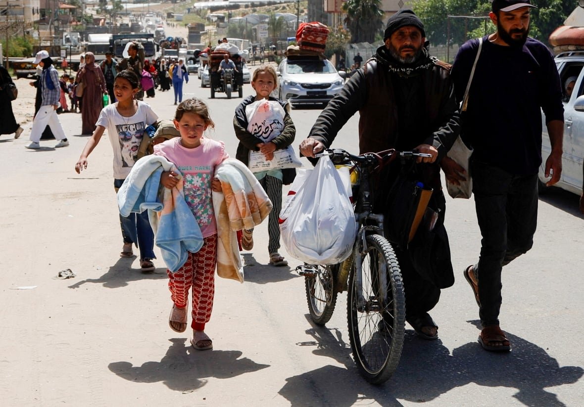 israel-palestinians-gaza-4 A group of people walk down a street holding belongings
