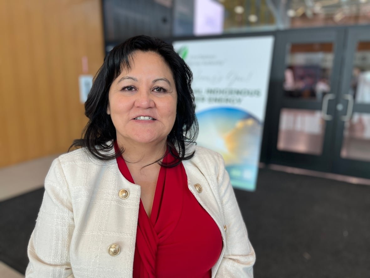 karen-ogen-ceo-of-the-first-nations-natural-gas-alliance A woman in a red shirt and white jacket is pictured at a conference inside a sportsplex.