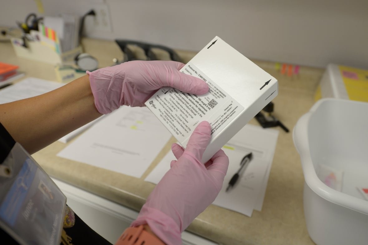 lyme-vaccine-1 A person with pink rubber gloves holds a small box.