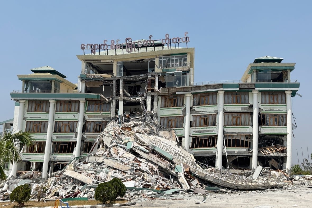 A damaged building is shown from a distance, with significant concrete rubble.