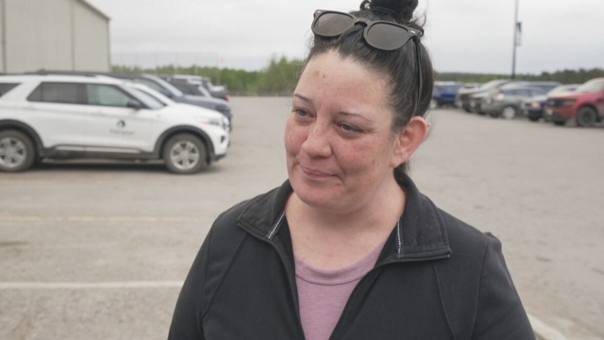 priscilla-markwart-lynn-lake-evacuee-june-3-2025 Woman wearing sunglasses atop her head and her dark hair in a bun looks off camera. She wears a black jacket over a light purple shirt