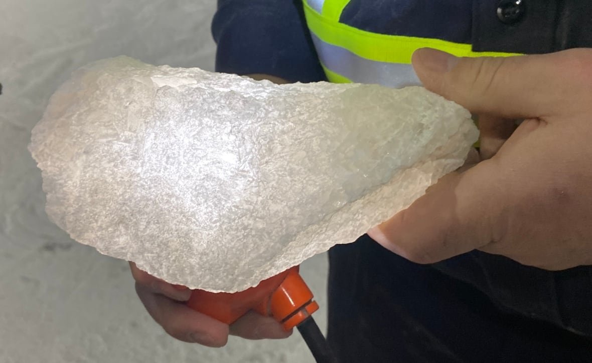 salt-from-picadilly-mine-is-some-of-the-purest-in-the-world-1 Miner holds a rock of salt about the size of a shoe while shining a light through it.