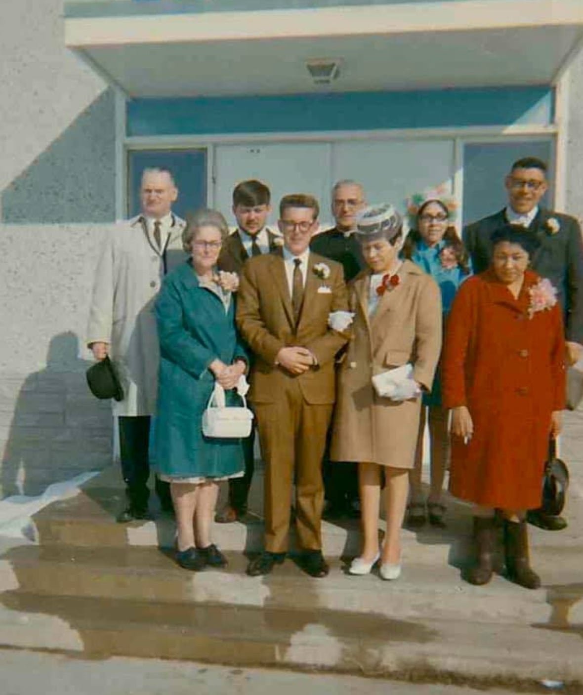 shannon-s-parents-wedding A bridal couple wearing brown and cream clothes stands with their wedding party on the steps of a courthouse.