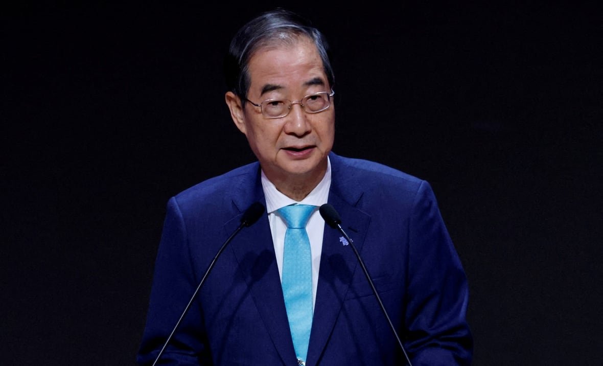 southkorea-politics A man wearing a blue tie and suit delivers a speech from a podium.