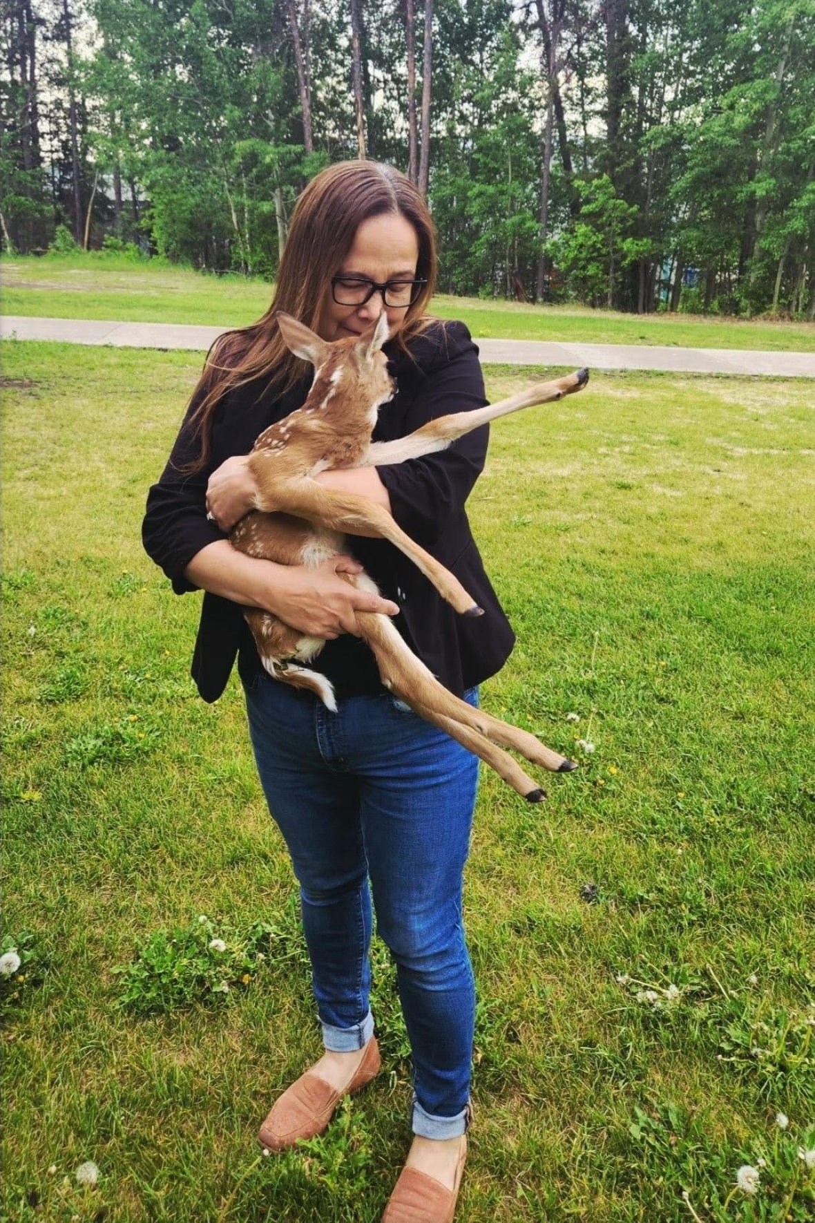 tammy-cook-searson-deer-fawn A woman holds a baby deer in her arms.