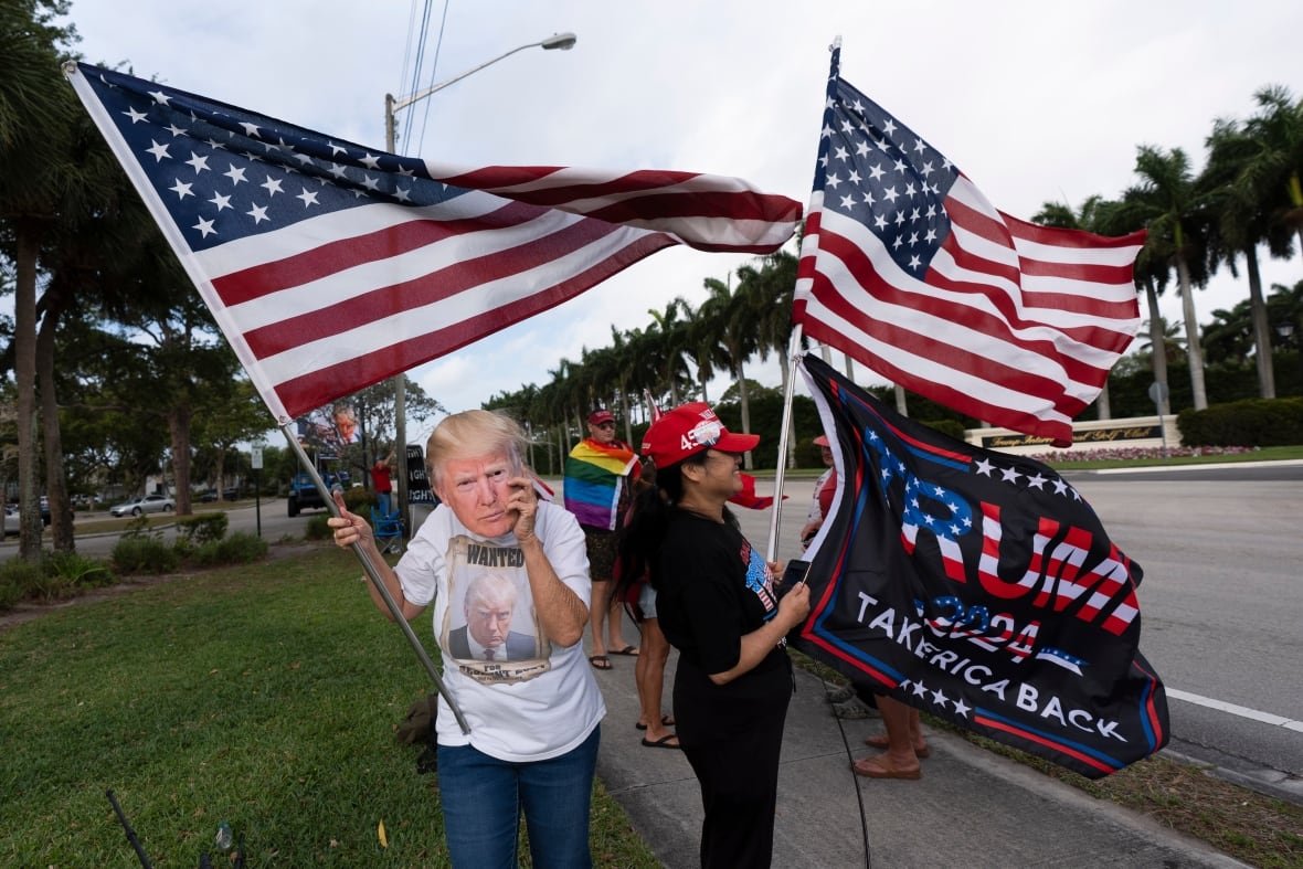 trump-supporters People wave flags as they demonstrate on the side of a road.