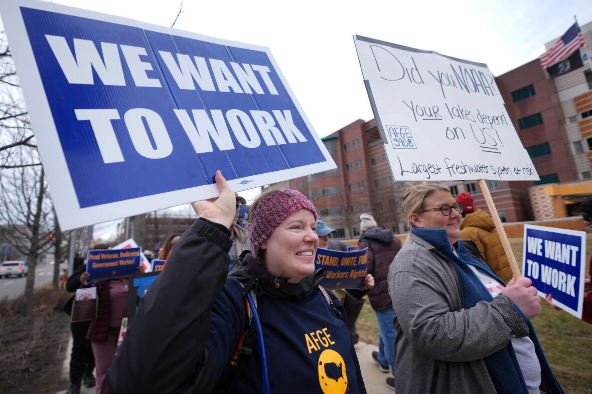 trump-workers-detroit Two people are seen holding signs that say "We want to work!" and "Did you NOAA? Your lakes depend on us!" as they stand outside and protest.